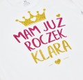 Białe body dziecięce MAM JUŻ ROCZEK z dowolnym imieniem, kolorystyka złoty i fuksja brokat